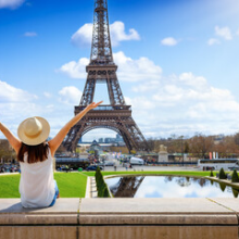 A tourist woman enjoys the beautiful view of the Eiffel Tower in Paris, France, during a sunny spring day.png